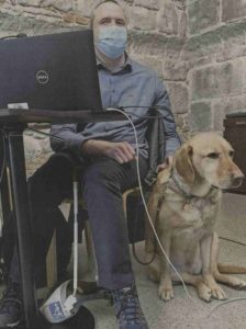 photo d'illustration Cédric devant son ordinateur. Son chien est assis à sa gauche.